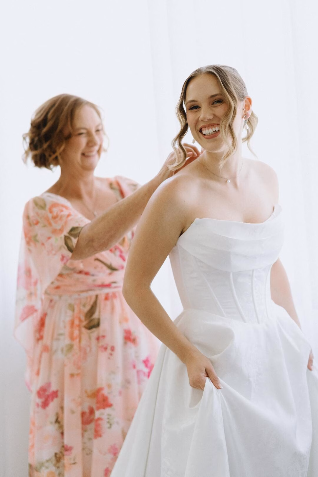 Bride laughing as her hair is finished